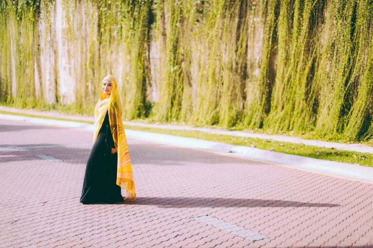 A Muslim woman in a vibrant hijab poses on a stone pavement, exuding confidence.