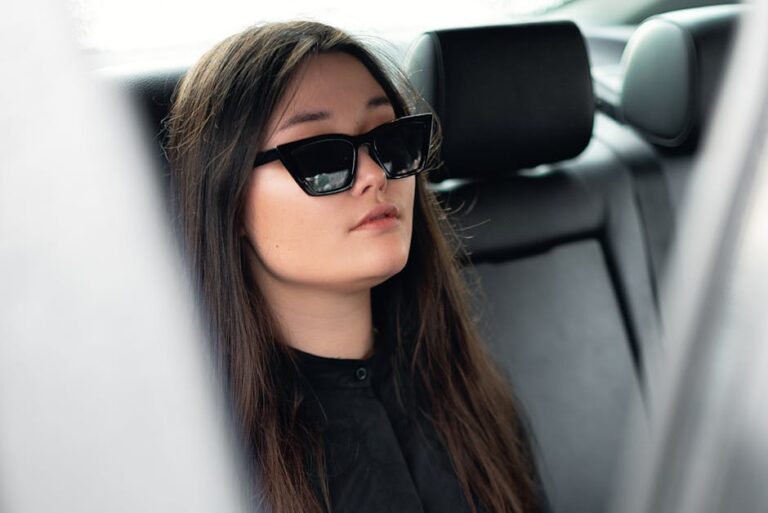 Asian woman wearing sunglasses relaxing in a car with leather seats.