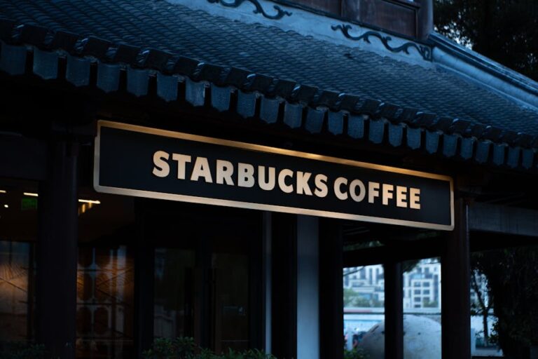Starbucks coffee shop sign displayed on a building with traditional design elements, captured at dusk.