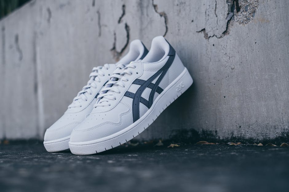 A pair of white and blue sneakers leaning against a textured concrete wall.