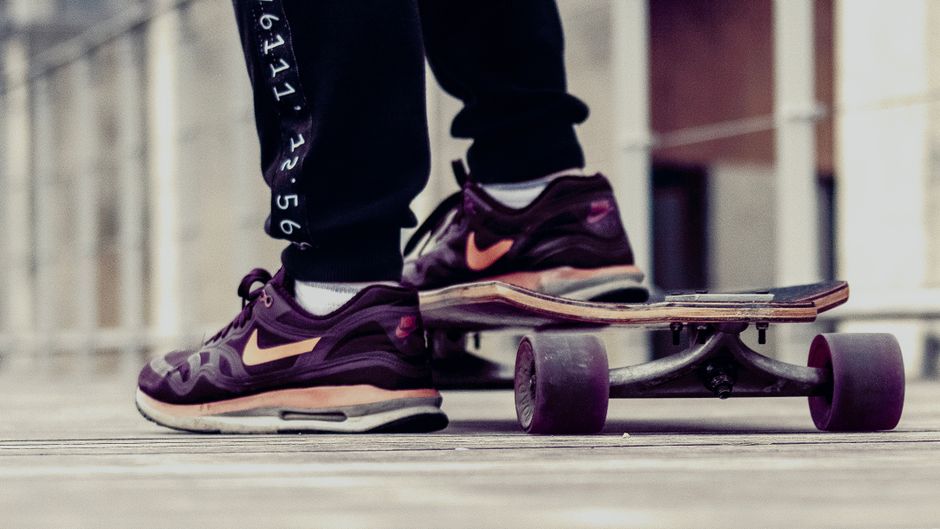 Close-up of a skateboarder in Nike sneakers on a wooden deck outdoors.