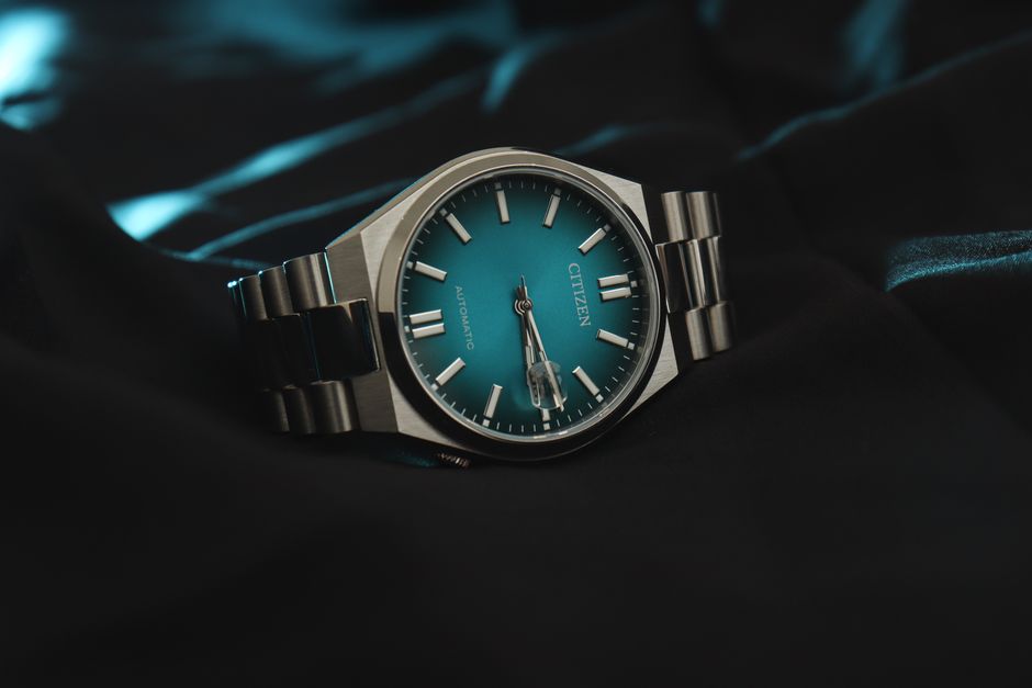 Stylish Citizen automatic wristwatch featuring a striking teal dial and stainless steel bracelet.