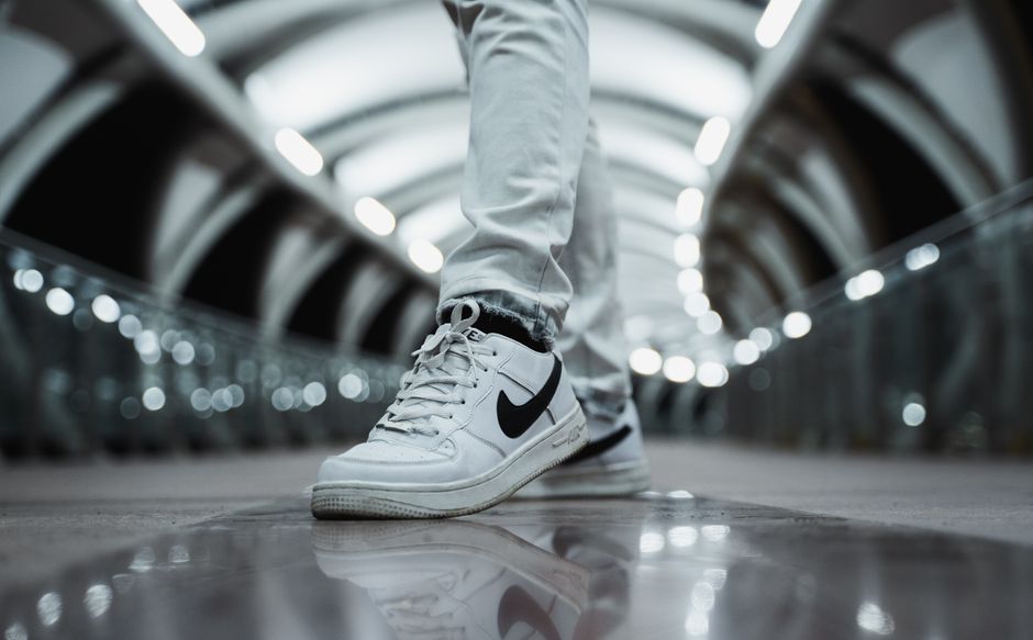 Close-up of white sneakers with a modern urban backdrop, highlighting style and nighttime city vibes.