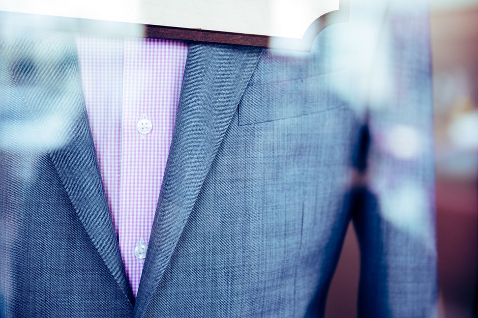 Elegant gray suit with a pink patterned shirt displayed in a store window, showcasing formal attire.